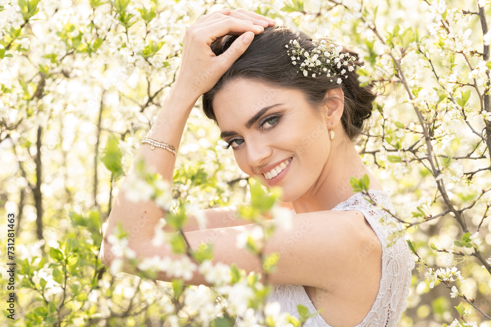 Beautiful brunette in a wedding dress in blooming trees.