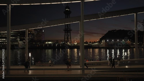 People walk along the promenade of the bay in Barcelona at night photo