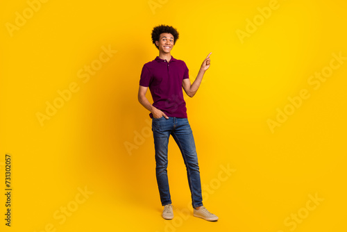 Photo of cheerful attractive stylish man wear trendy magenta polo demonstare empty space promo banner isolated on yellow color background © deagreez
