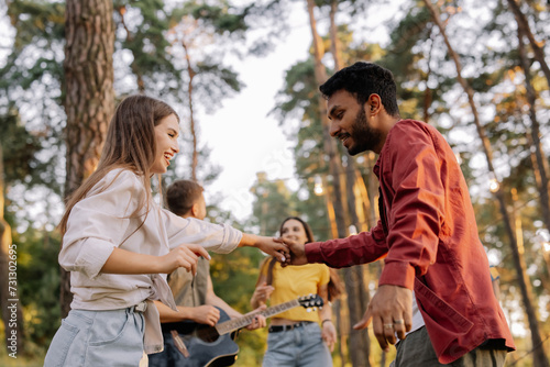 Multiracial couple dancing on the background of friends having fun