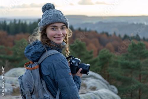 A girl, photographer is enjoying the view from a top of a mountain and holding a camera