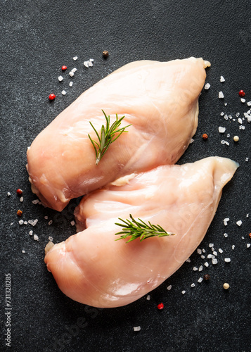 Chicken meat. Raw chicken breast with herb and spices at black background. Top view.