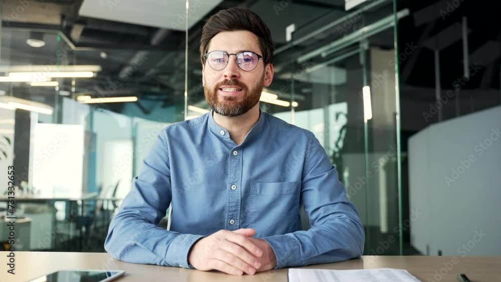 Webcam view. Confident businessman talking on a video call looking at the camera sitting at workplace in office. Entrepreneur has a business meeting. Manager speaks remotely at an online conference