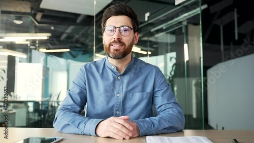 Webcam view. Confident businessman talking on a video call looking at the camera sitting at workplace in office. Entrepreneur has a business meeting. Manager speaks remotely at an online conference