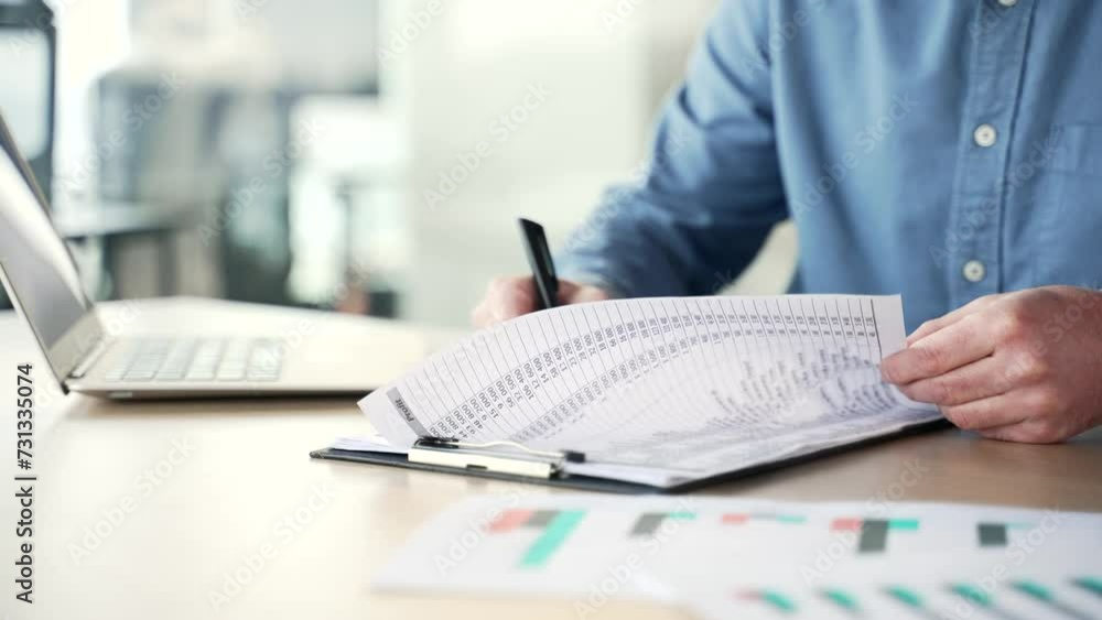 Close up of a man's hand signing documents at a desk at a workplace in a business office. Businessman in a blue shirt looks through the folder with documentation and signs the contract with a pen