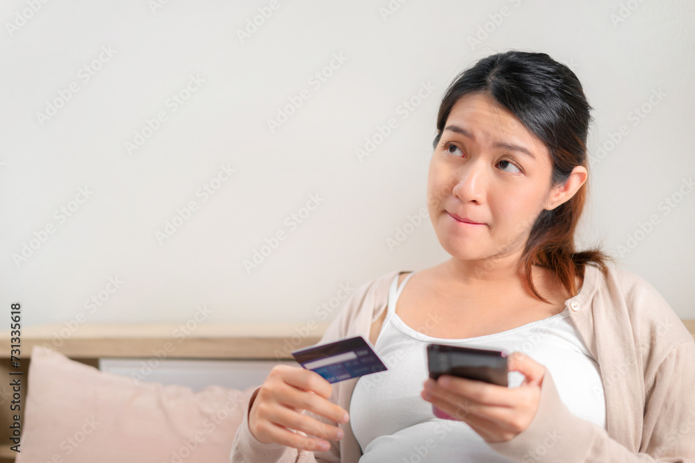 Asian pregnant woman holding credit card and using mobile smartphone shopping online at home, Prepare for birth, New normal and social distancing concept, Maternity prenatal care concept. Asian pregnant woman holding credit card and using mobile smartphone shopping online at home, Prepare for birth, New normal and social distancing concept, Maternity prenatal care concept.