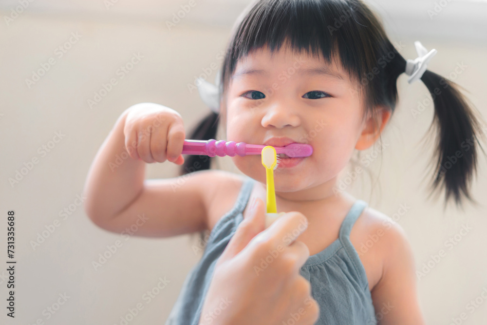 Asian mother and daughter brushing their teeth together, Mom teaching his daughter how to brush teeth, Oral health concept Asian mother and daughter brushing their teeth together, Mom teaching his daughter how to brush teeth, Oral health concept