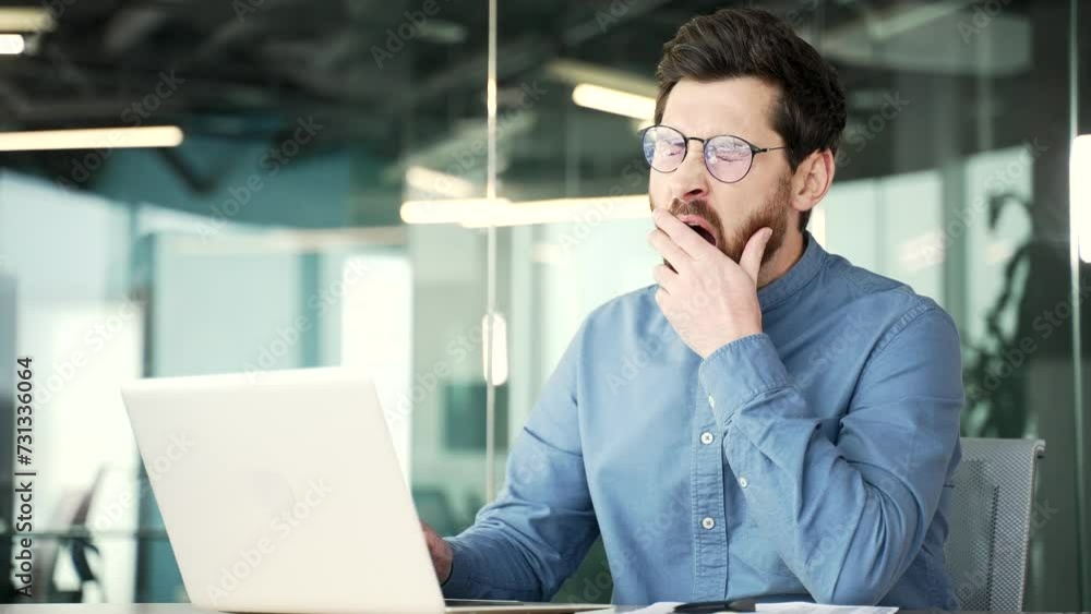Overworked handsome bearded businessman feels tired and wants to sleep working on laptop sitting at workplace at desk in business office. Sleepy exhausted man yawns, closes his eyes. Overload at work Overworked handsome bearded businessman feels tired and wants to sleep working on laptop sitting at workplace at desk in business office. Sleepy exhausted man yawns, closes his eyes. Overload at work
