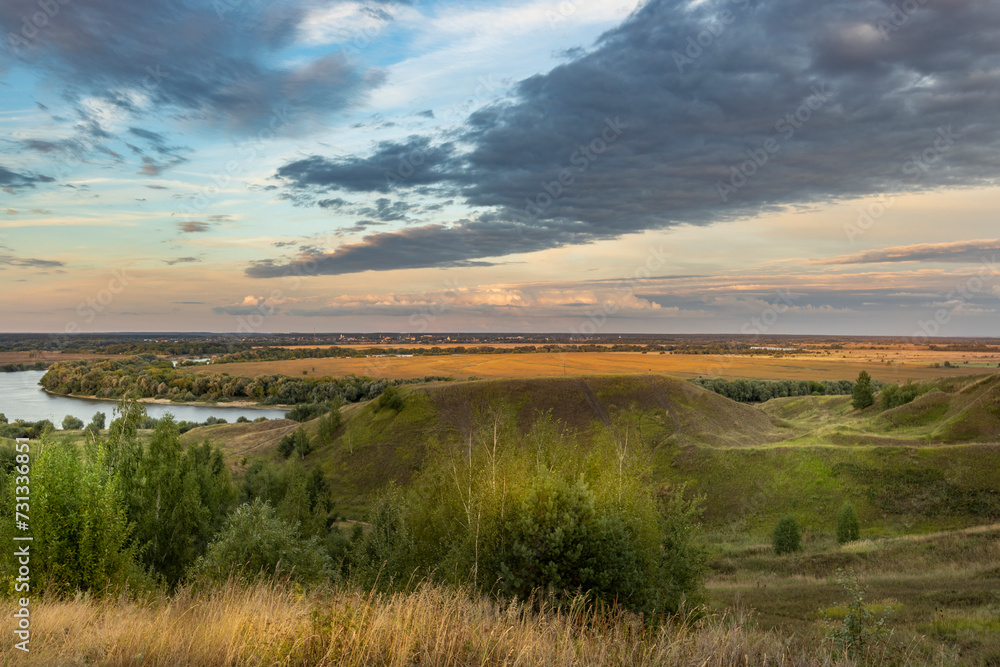 Autumn rural landscape, hills in the foreground, agricultural fields across the river stretching to the horizon, sunset sky over majestic open spaces. Autumn rural landscape, hills in the foreground, agricultural fields across the river stretching to the horizon, sunset sky over majestic open spaces.