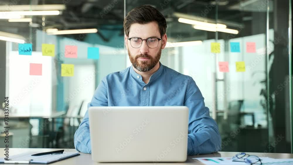 Focused businessman typing on a laptop sitting at a workplace in office. Bearded manager in glasses working in computer application, banking, texting a client, chatting online. busy with a project Focused businessman typing on a laptop sitting at a workplace in office. Bearded manager in glasses working in computer application, banking, texting a client, chatting online. busy with a project