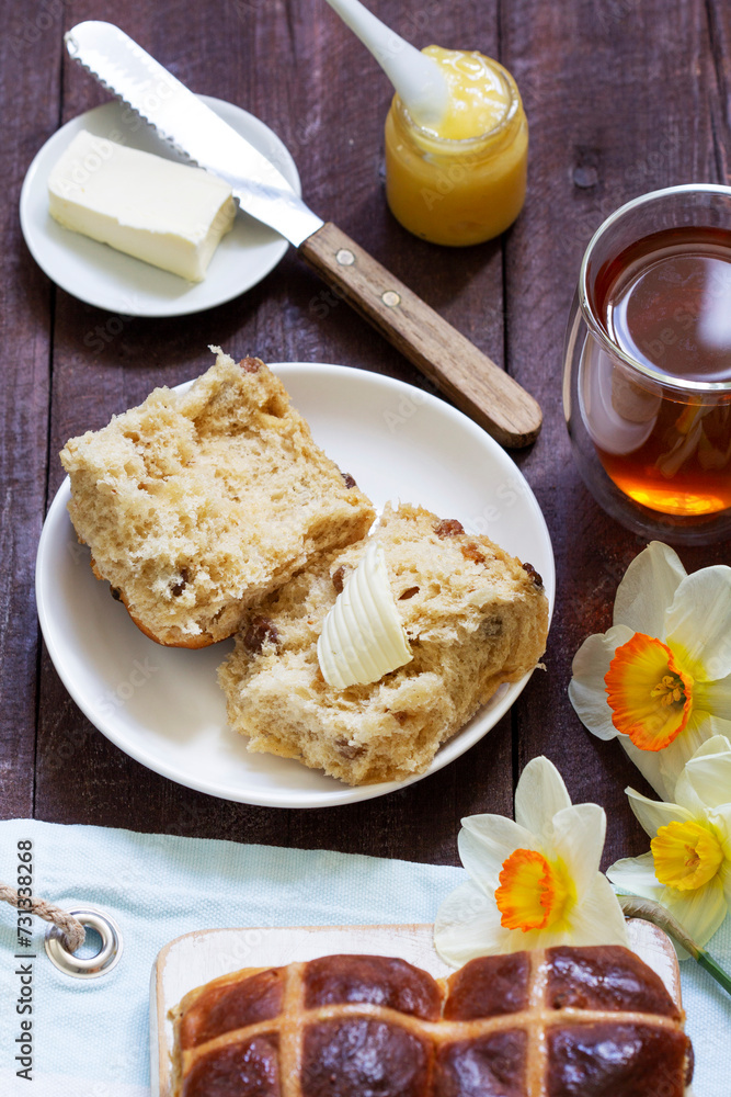 Cross buns served with butter, honey and tea. Easter breakfast.