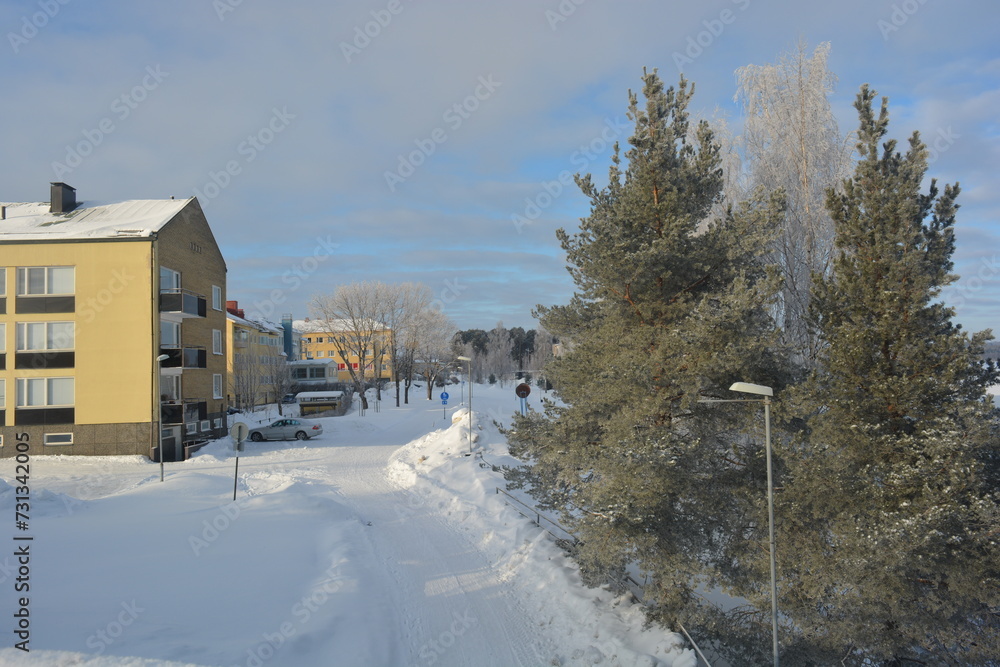 A real snowy winter in Varkaus, Finland. Finnish houses in white snow with trampled roads, beautiful trees, fir trees, spruces growing in wildlife.