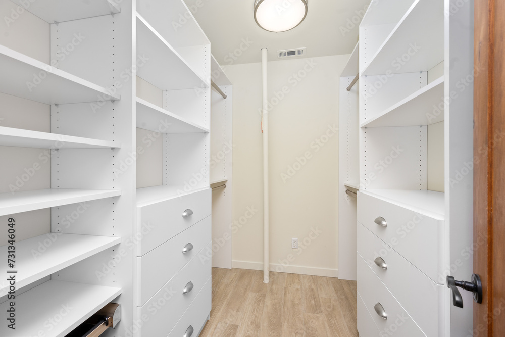 an open closet with white drawers and shelves on each side an open closet with white drawers and shelves on each side