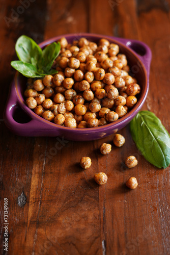 Basil and paprika roasted chickpeas on wooden background.