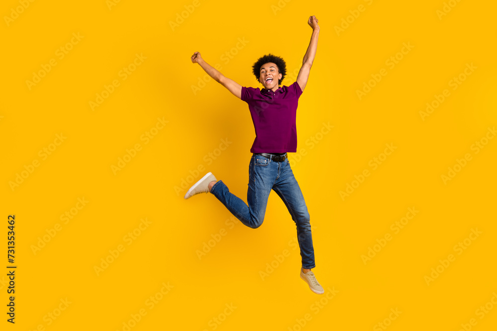 Full length photo of overjoyed glad man wear trendy violet clothes jump up raise hands fist scream yes isolated on yellow color background