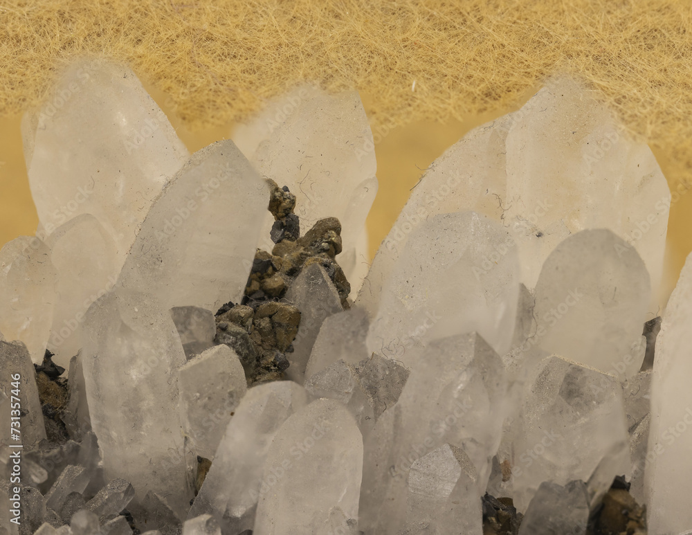 Macro shot of clear quartz crystal cluster against a yellow background