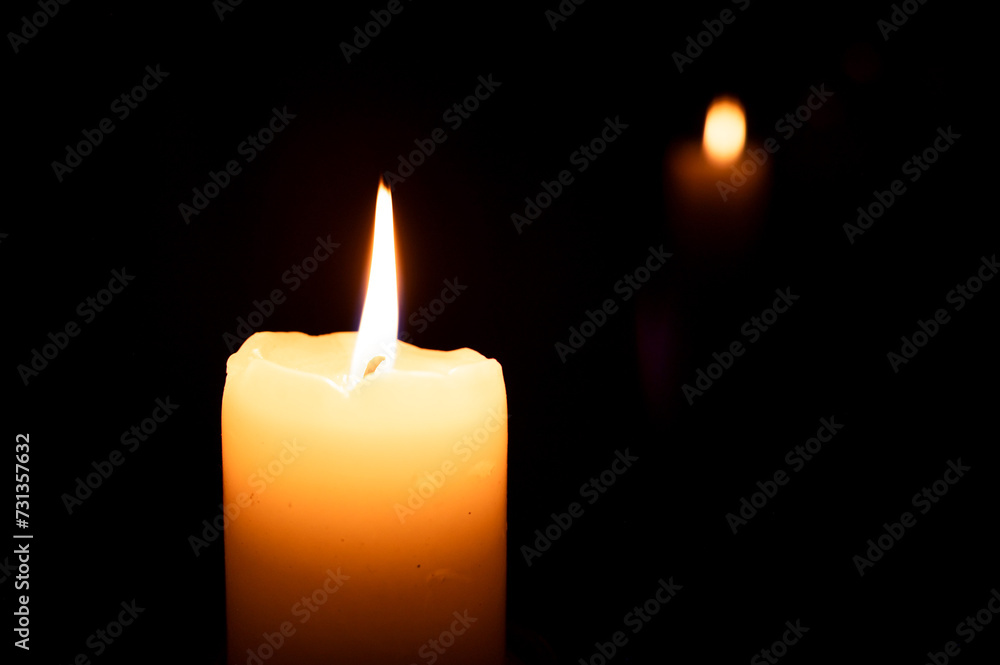 lit candle in the dark and its reflection in the background lit candle in the dark and its reflection in the background