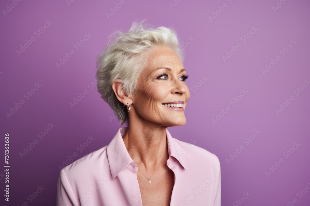 Portrait of a beautiful senior woman smiling at the camera on a purple background