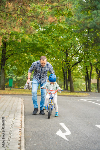 Father teaches child daughter to ride public bike on traffic playground in Prague, Czech republic
