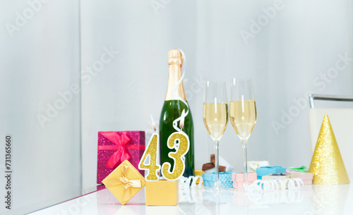 Date of birth with number  43. Festive Champagne in glasses with gift boxes, anniversary postcard. Happy birthday golden candles.