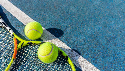 Holliday sport composition with yellow tennis balls and racket on a blue background of hard tennis court. Sport and healthy lifestyle. The concept of outdoor game sports. Flat lay © Amli