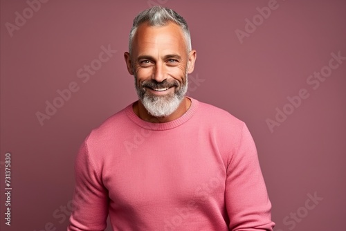 Portrait of a handsome senior man with grey hair and a pink sweater.