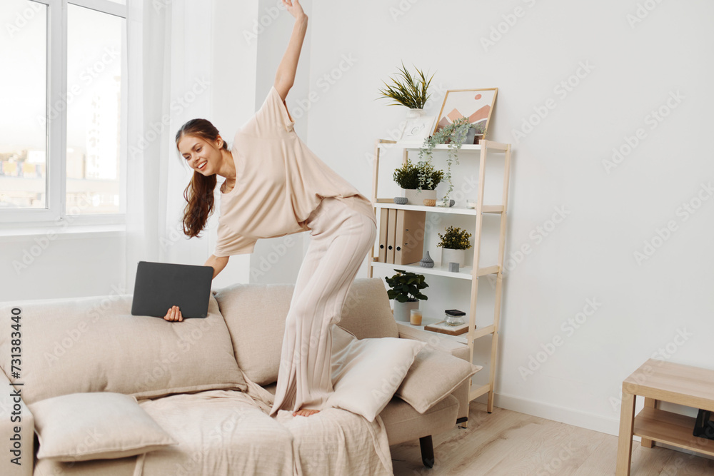 Smiling woman working on laptop in cozy living room, enjoying freelance job in modern domestic setting Smiling woman working on laptop in cozy living room, enjoying freelance job in modern domestic setting