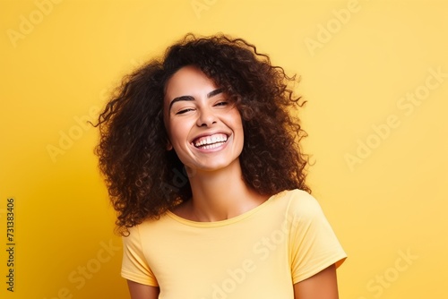 Portrait of a beautiful young african american woman laughing over yellow background