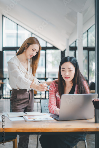 Business team concept, Focused team members evaluate information on a laptop while discussing their business strategy in a modern workspace.