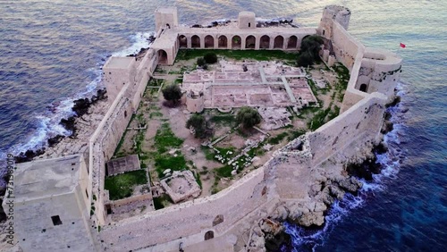 Behold Kizkalesi's architectural splendor in aerial views 12th-century Byzantine castle massive ruins on Mersin sunset Mediterranean coast embodying the region's historical and architectural legacy photo