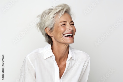 Portrait of happy mature woman laughing and looking at camera isolated over white background