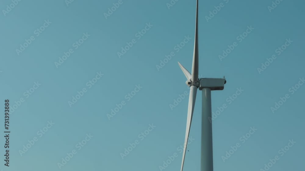 Close up of wind turbine spinning in windmills farm for energy production Close up of wind turbine spinning in windmills farm for energy production