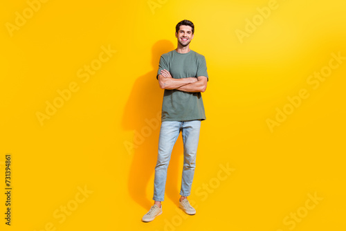 Full length photo of cool confident guy wear khaki t-shirt arms crossed smiling isolated yellow color background