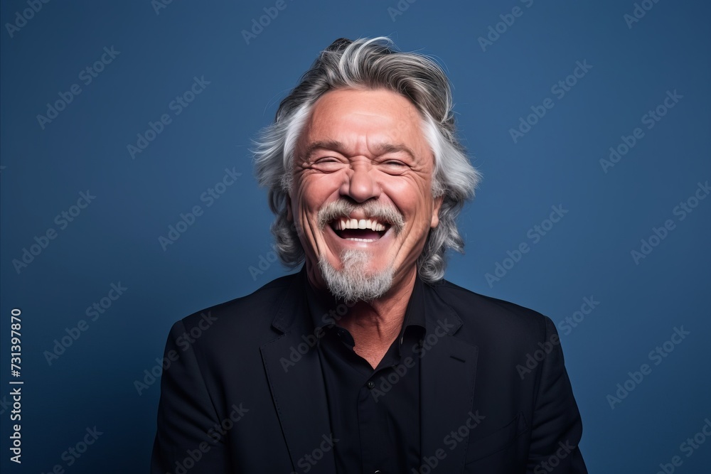 Portrait of a happy senior man laughing and looking at camera on blue background
