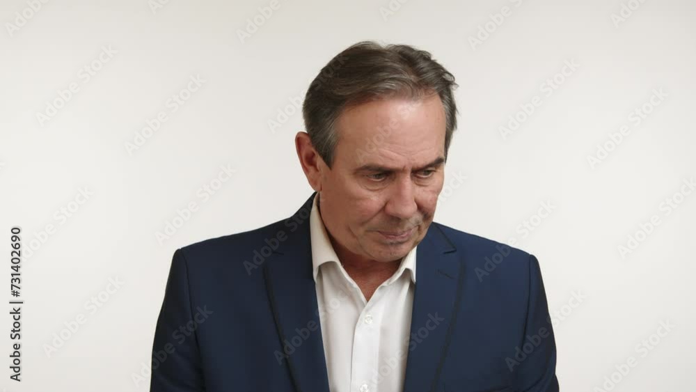 A mature man in a suit shows signs of discomfort and guilt, looking down with a regretful expression, possibly reflecting on a mistake or a moment of embarrassment. Camera 8K RAW. 