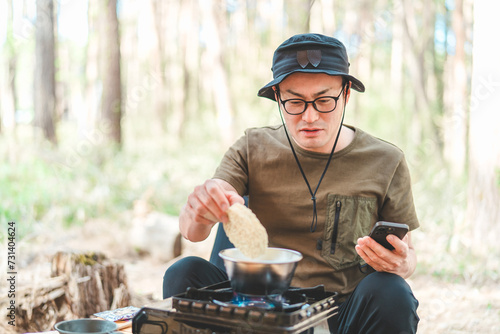 キャンプ飯でインスタントラーメン・袋麺を食べるキャンパーの男性 