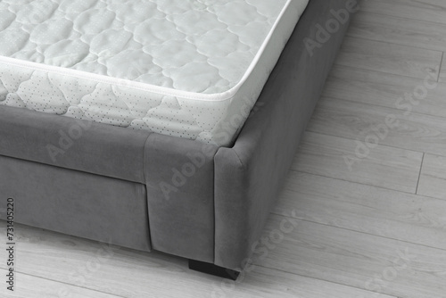 New soft mattress on grey bed indoors, closeup. Space for text