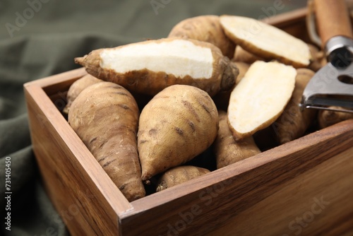 Foto Tubers of turnip rooted chervil and peeler in wooden crate on table, closeup