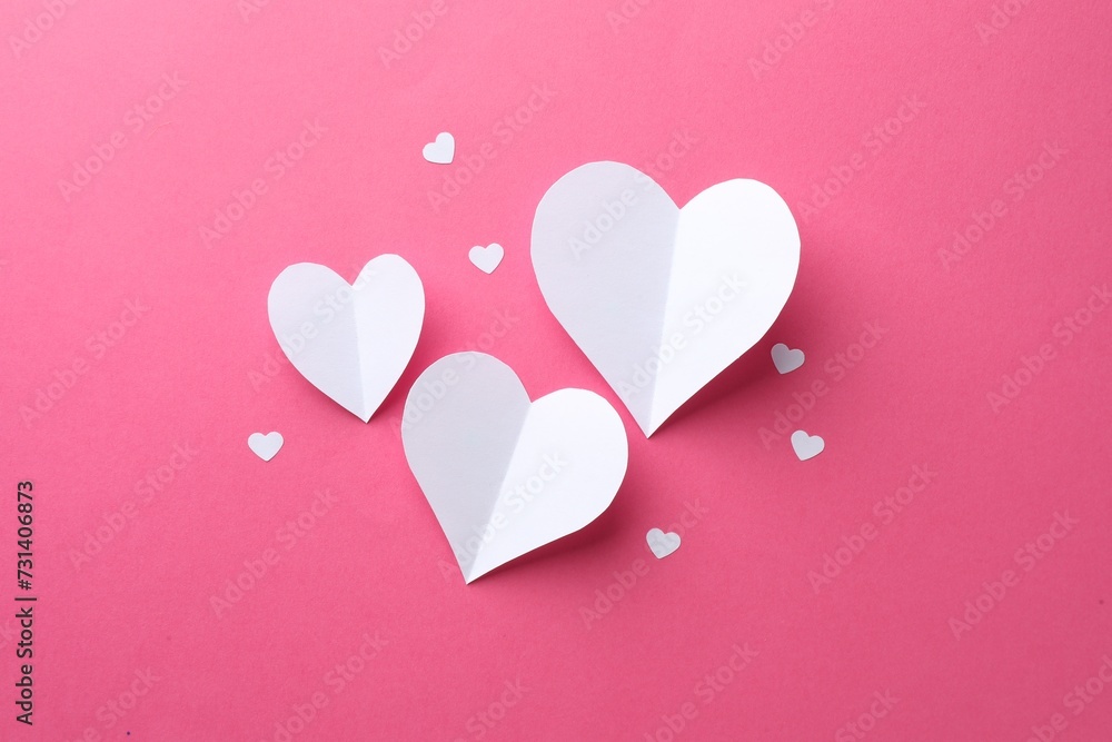 White paper hearts on pink background, flat lay