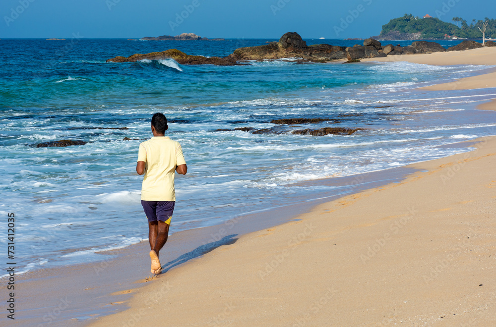 A man runs along the coast of the island of Sri Lanka. Back view.