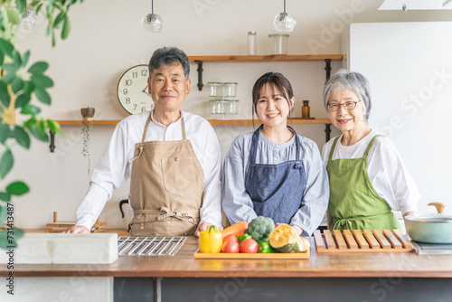キッチンで料理する高齢者夫婦と若い日本人（家事代行・介護） 