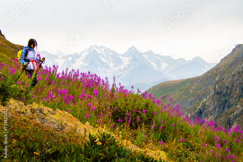 Side view tracking fit sporty female hiker with nordic walk pols on viewpoint uphill in green hiking trail in caucasus mountains .Recreational activities and healthy lifestyle photo