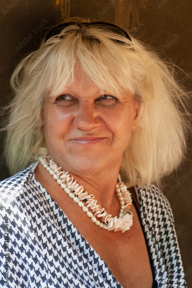 smiling middle age blonde woman portrait, wearing a traditional necklace and casual clothing