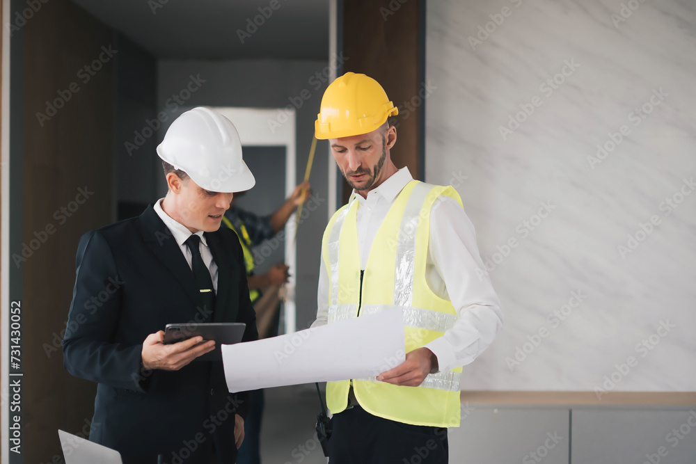 professional engineers in safety vests and hardhats working with blueprints and showing construction, Industrial engineers in hard hat discuss new project, they work in manufacturing factory. professional engineers in safety vests and hardhats working with blueprints and showing construction, Industrial engineers in hard hat discuss new project, they work in manufacturing factory.