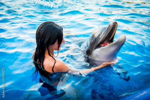 Portrait of young Caucasian woman smile with dolphin in pool water of Batumi delphinarium. Swim with dolphin experience concept