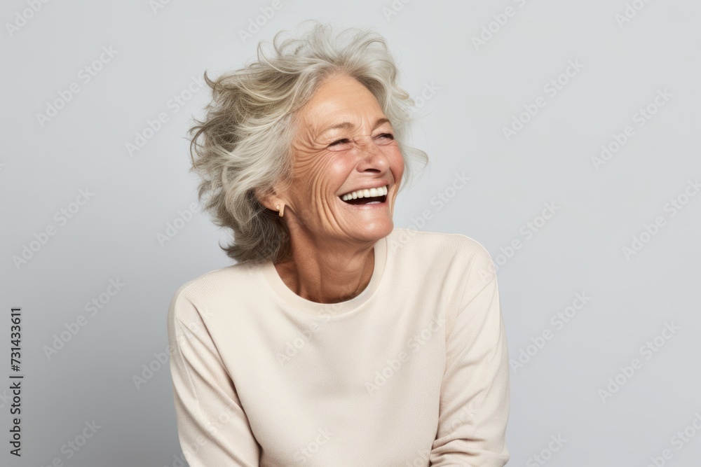 Happy senior woman laughing and looking at camera, isolated on grey background Happy senior woman laughing and looking at camera, isolated on grey background