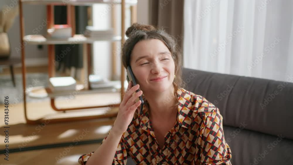 Close handheld shot of smiling woman talking on phone in living room Close handheld shot of smiling woman talking on phone in living room