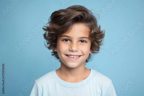 Portrait of a smiling little boy with curly hair on blue background