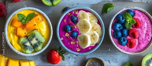 Top view of a serving tray with 3 vibrant tropical fruit smoothie bowls, perfect for a healthy vegan breakfast during the summer.