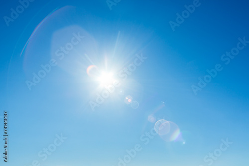 青空に輝く太陽、映り込むフレア photo